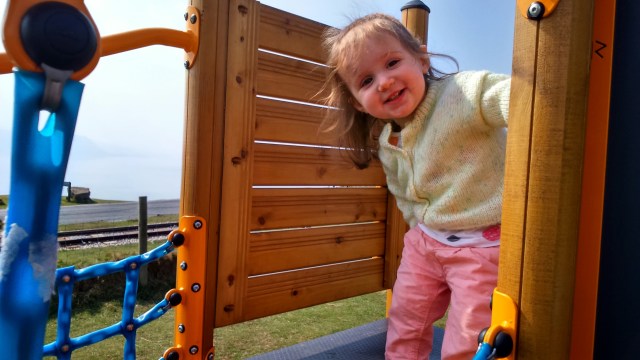 Smiling toddler on a climbing frame. A fun family holiday in North Wales at SpookyMrsGreen.com mindful parenting and modern pagan lifestyle blog.