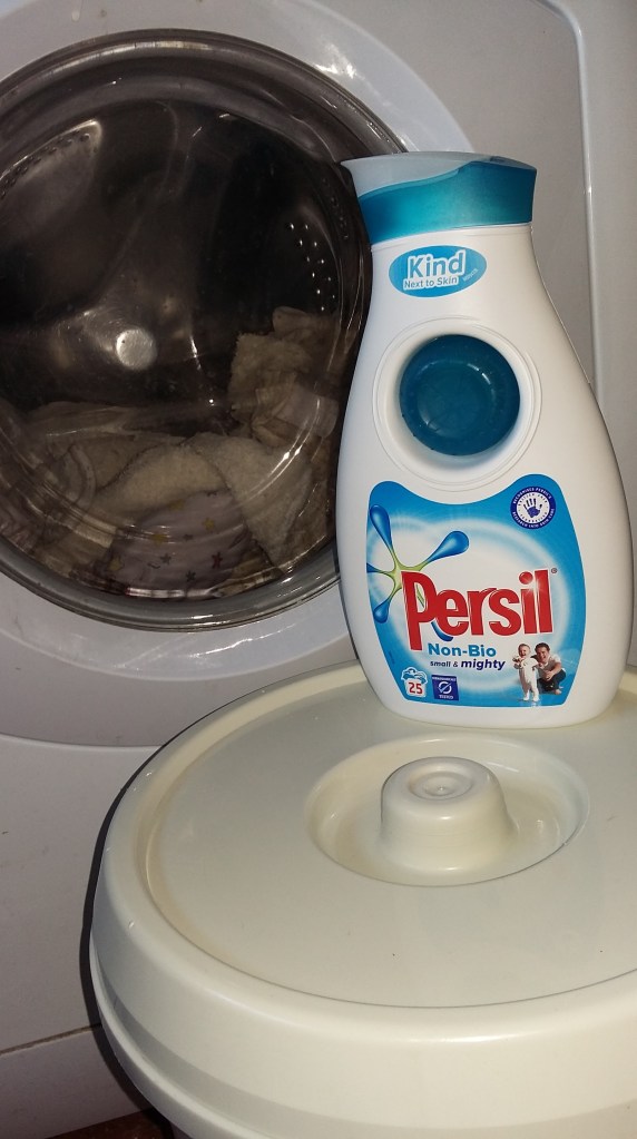 Image of a white washing machine with a nappy bucket and a bottle of Persil washing liquid. #MummyMonday Washing Cloth Nappies #BrightFuture Persil Unilever Promotion at SpookyMrsGreen.com mindful parenting and modern pagan lifestyle blog.