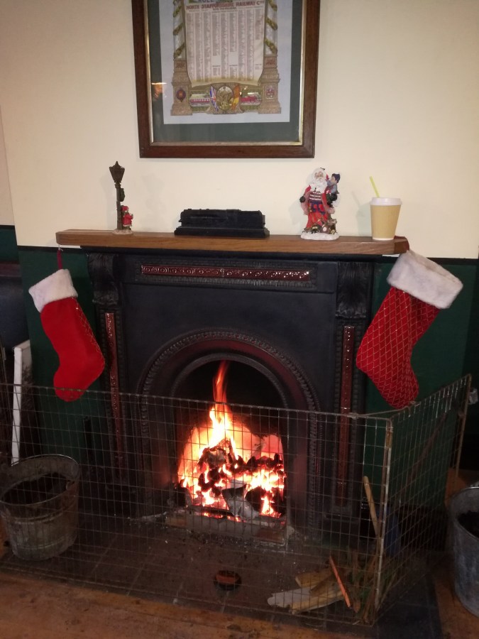 Image of a traditional coal fire burning in the grate with red Christmas stockings hung on the mantlepiece. #MummyMonday Christmas at Churnet Valley Railway in Staffordshire by SpookyMrsGreen.com mindful parenting and modern pagan lifestyle blog.
