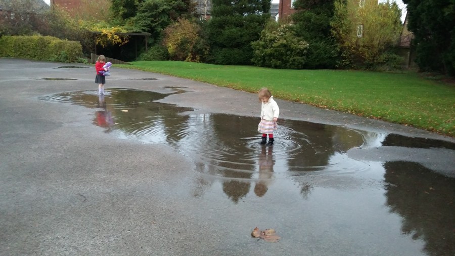 Image of two little girls jumping in puddles on a carpark after heavy rain. #MummyMonday Puddle Jumping Nostalgia image copyright SpookyMrsGreen.com mindful parenting and modern pagan lifestyle blog.
