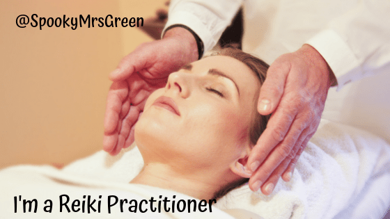 Photo of a woman lying on a therapy bed receiving reiki energy healing from a reiki practitioner. Text reads "I'm a Reiki practitioner @SpookyMrsGreen."