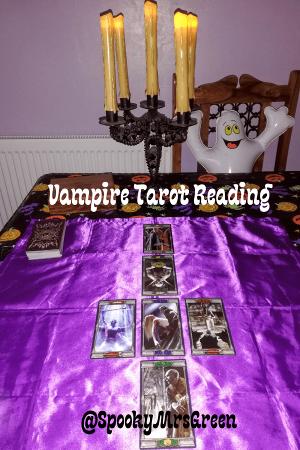 Black candelabra with glowing candles and a white inflatable ghost smiling sitting at a table. Vampires Tarot of the Eternal Night Tarot cards Tarot card reading on purple cloth SpookyMrsGreen.com pagan lifestyle blog.