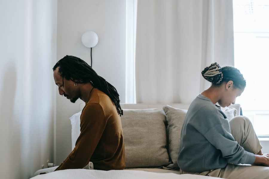 concerned black couple sitting on bed in misunderstanding at SpookyMrsGreen.com mindful parenting and modern pagan lifestyle blog.