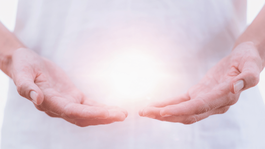 Image of human hands holding a glowing ball of light that represents Reiki healing energy. Goldstone Reiki distance reiki treatment.