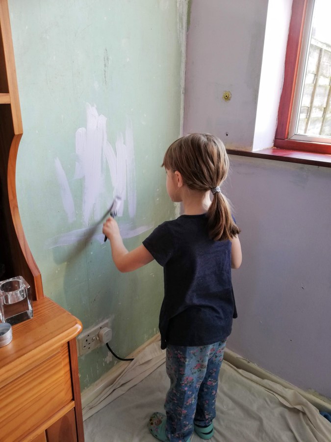 Image of a girl painting a wall in the house. My Home Renovation: Dining Room Makeover at SpookyMrsGreen.com mindful parenting and modern pagan lifestyle blog.