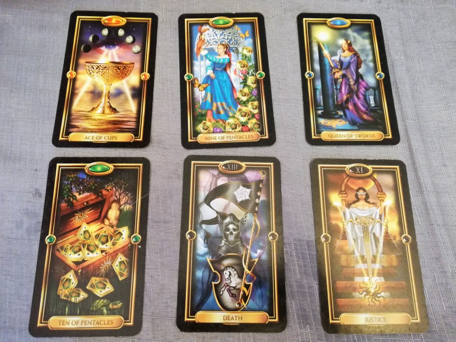 Image of Gilded Tarot cards on a grey cloth. August Tarot Reading by professional Tarot reader Catherine Green of SpookyMrsGreen.com pagan lifestyle blog.