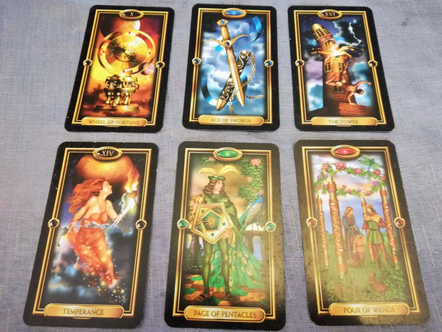 Image of Gilded Tarot cards on a grey cloth. August Tarot Reading by professional Tarot reader Catherine Green of SpookyMrsGreen.com pagan lifestyle blog.