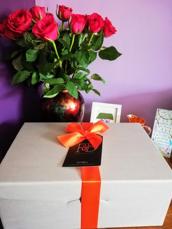 Image of a boxed gift hamper with red ribbon and a bouquet of red roses. #ProductReview Gift Hampers UK with SpookyMrsGreen.com mindful parenting and modern pagan lifestyle blog.