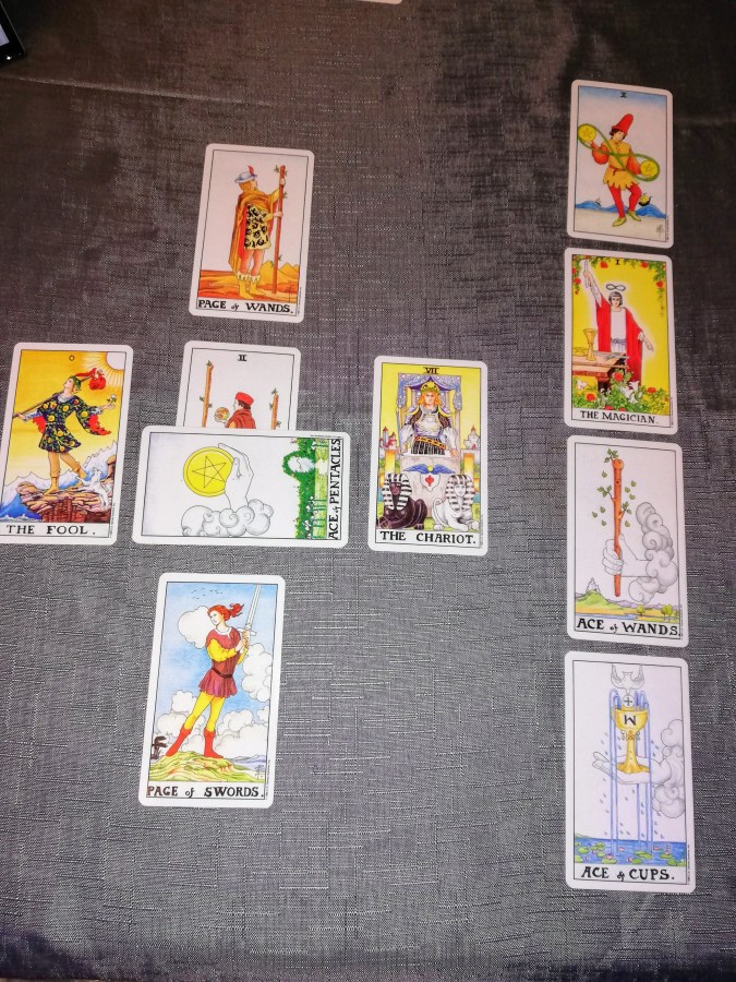 Image of Universal Rider Waite-Smith Tarot cards on a grey sofa. Celtic Cross Tarot Reading by professional Tarot reader Catherine Green of SpookyMrsGreen.com pagan lifestyle blog.