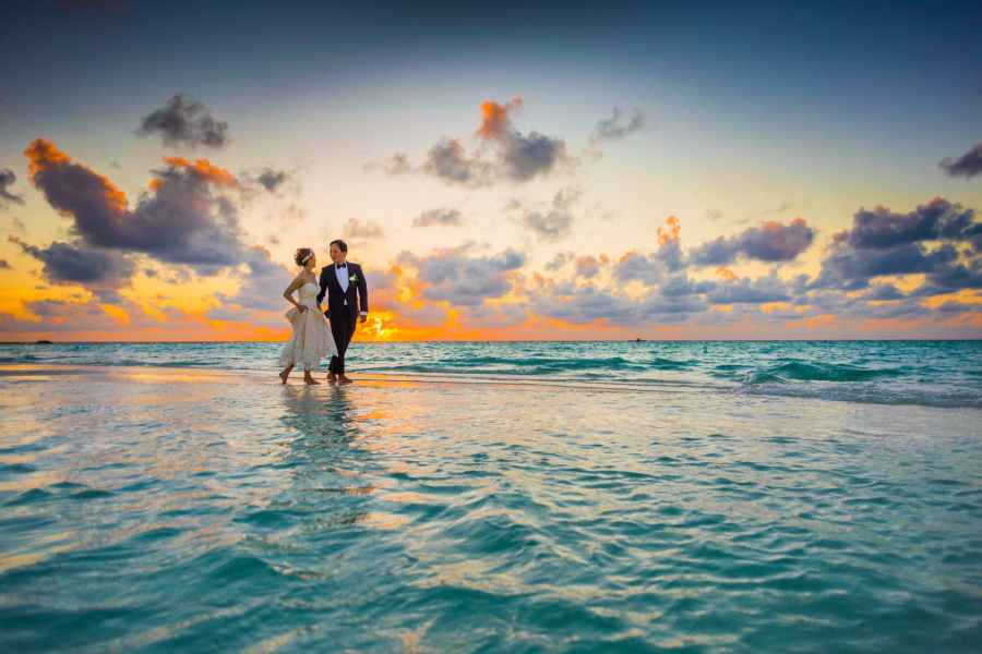Bride and Groom walking on water with orange sunset behind them. Photo featured at SpookyMrsGreen.com mindful parenting and modern pagan lifestyle blog.