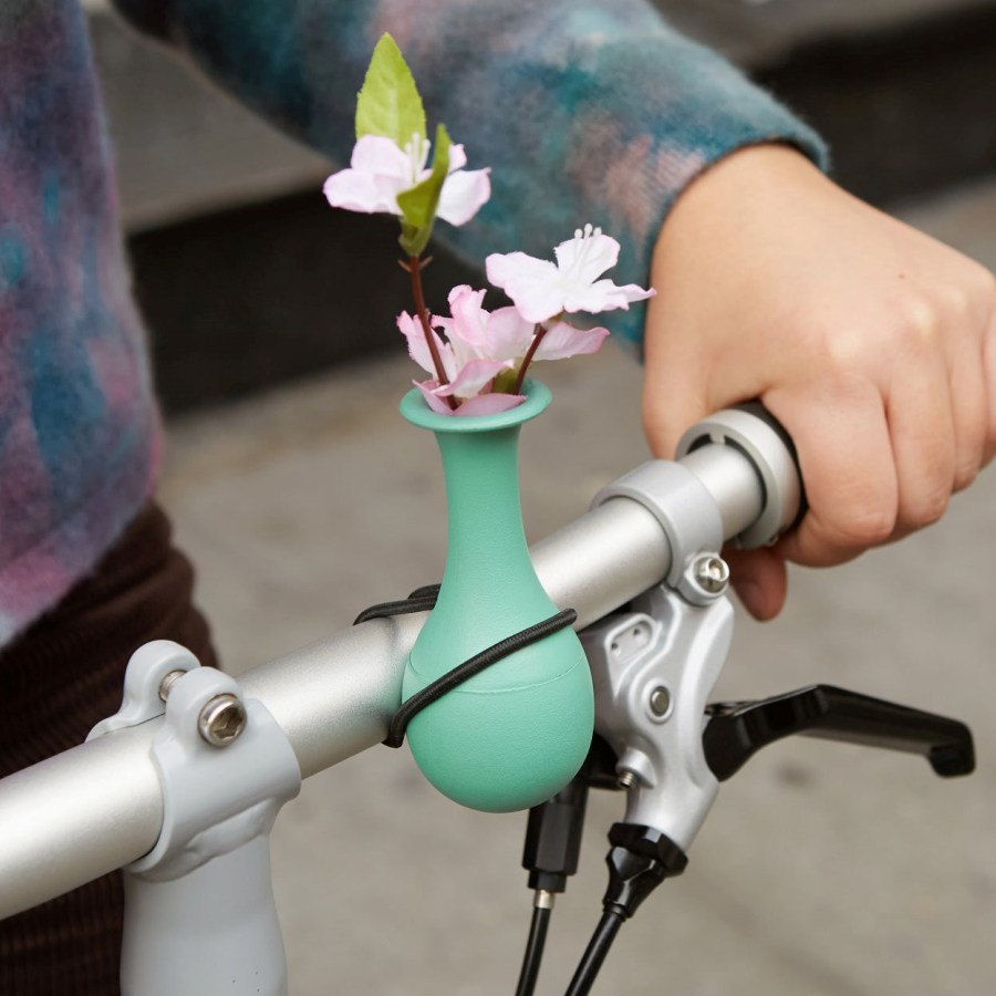 Image of a person riding a bike with a small vase of flowers attached to the handle bar. Bike Vase from Kikkerland quirky gift ideas featured at SpookyMrsGreen.com mindful parenting and modern pagan lifestyle blog.