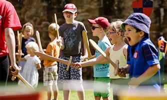 A group of children playing with wooden swords pretending to be knights or warriors. 3 for 2 on All Children's Weaponry from English Heritage Shop affiliated with SpookyMrsGreen.com mindful parenting and modern pagan lifestyle blog.