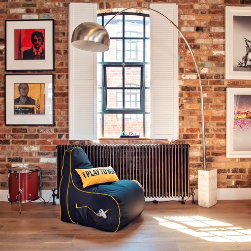 Image of a trendy living space with a gaming chair next to a window with a stylish floor lamp and pictures on the wall. Game Over Gaming Bean Bags and Chairs affiliated with SpookyMrsGreen.com mindful parenting and modern pagan lifestyle blog.