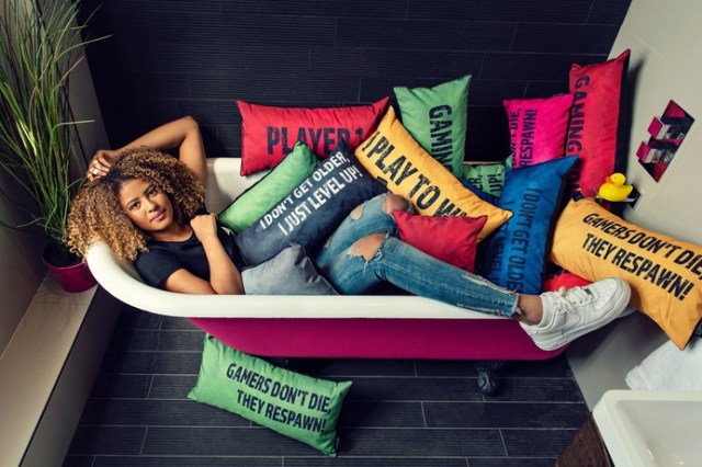 Image of a woman lying in a bath beneath a pile of gaming cushions with gaming slogans printed on them. Game Over Gaming Bean Bags and Chairs affiliated with SpookyMrsGreen.com mindful parenting and modern pagan lifestyle blog.