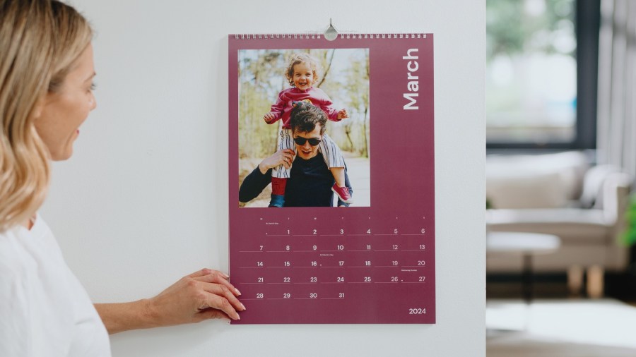 Image of a woman smiling and looking at a Personalised Photo Calendar from Popsa UK affiliated with SpookyMrsGreen.com mindful parenting and modern pagan lifestyle blog.