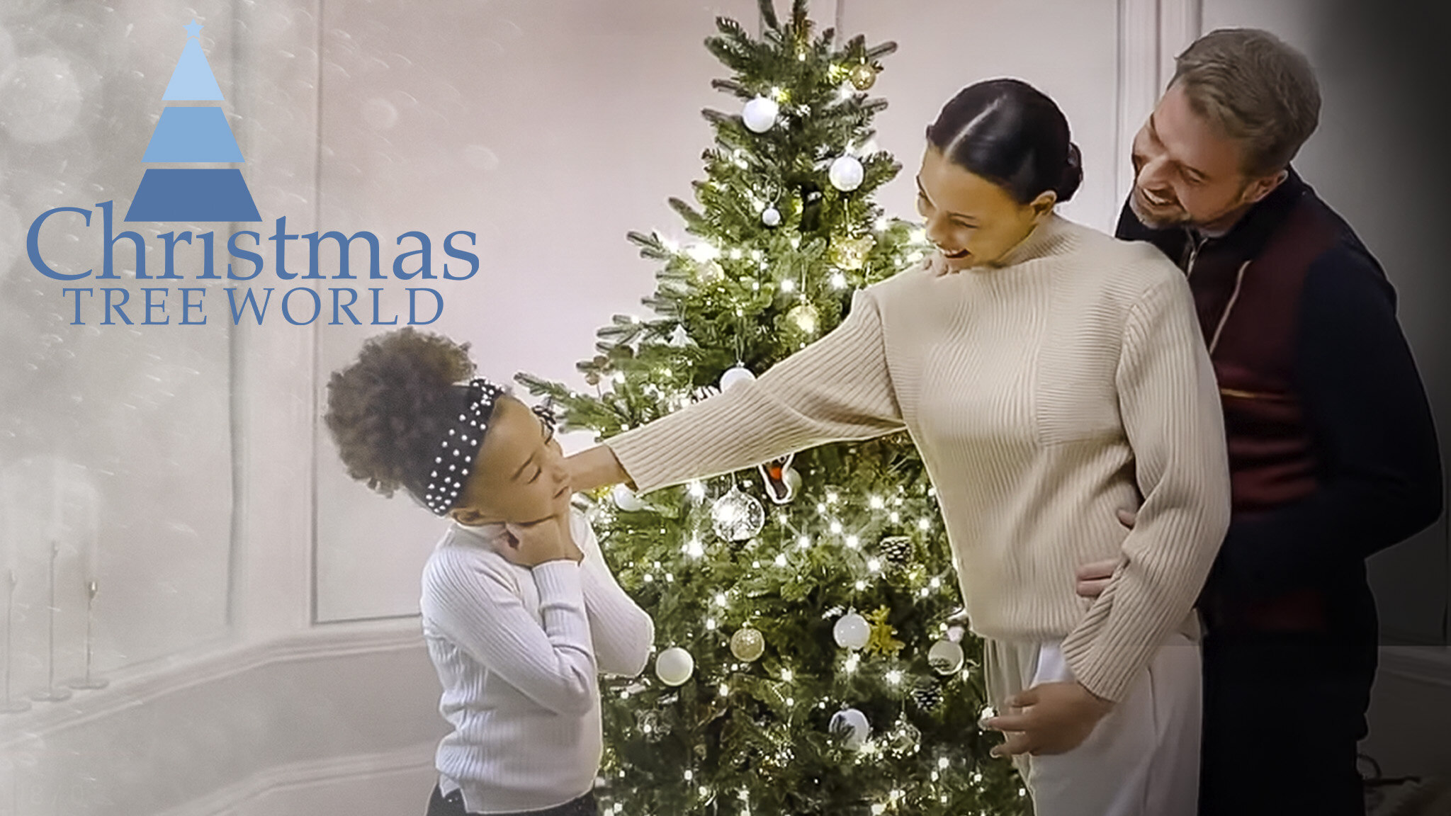 Text reads, "Christmas Tree World." Cosy image of a Christmas tree with warm lights and a young family standing around the tree smiling and having fun together. Christmas Tree World affiliated with SpookyMrsGreen.com mindful parenting and modern pagan lifestyle blog.