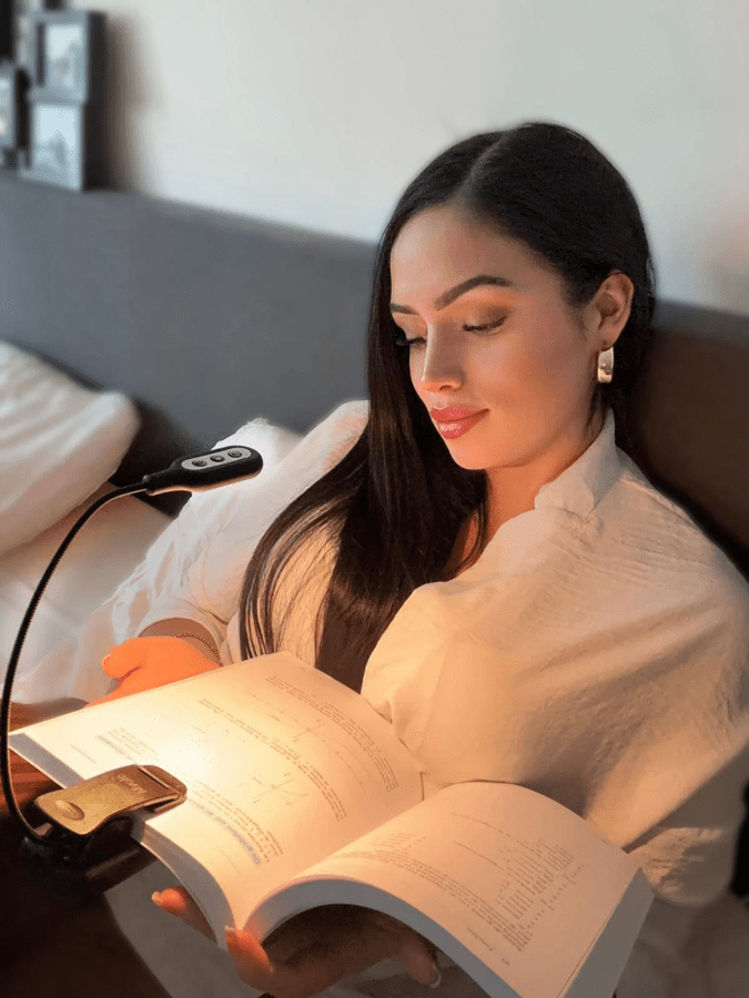 Image of a woman sitting on a sofa reading a book with a reading light attached from Mvolo affiliated with SpookyMrsGreen.com mindful parenting and modern pagan lifestyle blog.