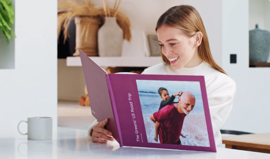 Image of a girl looking at photos in a photo book and smiling. Fantastic June Savings at Popsa affiliated with SpookyMrsGreen.com mindful parenting and modern pagan lifestyle blog.