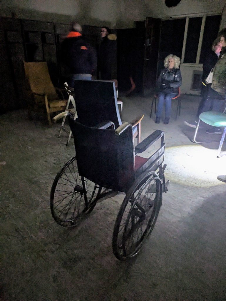 Image of a group of paranormal investigators in a derelict hospital room at Newsham Park Haunted Hospital Ghost Hunt performing a vigil calling to ghosts.